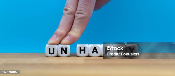 Dice Form The Word Unhappy While Two Fingers Push The Letters Un Away In Order To Change The Word To Happy Stock Photo - Download Image Now