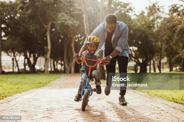 Father Teaching His Son Cycling At Park Stock Photo - Download Image Now - Child, Father, Cycling