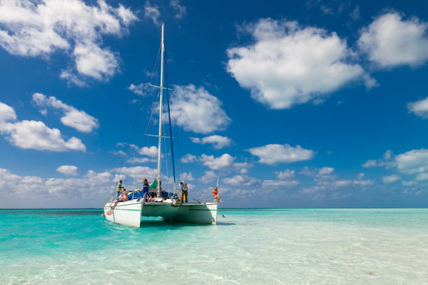 Group of unidentified tourists travel on a catamaran near the island of Kayo Largo.  White catamaran on a background of blue sky and azure water/ People relaxing.