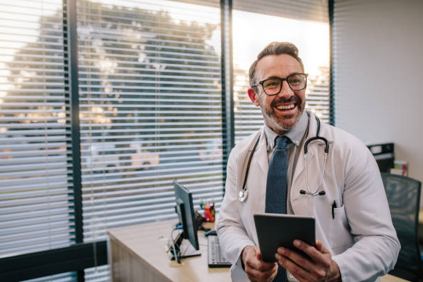 médico con tableta digital en su oficina - looking away fotos fotografías e imágenes de stock