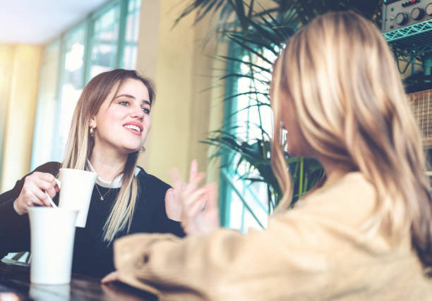 istock Young women drinking coffee and talking at cafe 1126789872
