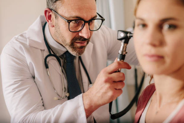 ENT doctor checking ear with otoscope of woman patient ENT doctor checking ear with otoscope of woman patient at hospital. Physician examining ear of female patient with an instrument. ent stock pictures, royalty-free photos & images