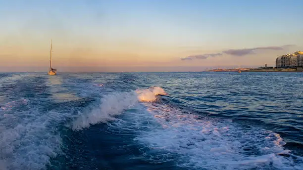 Boat wake on the Maltese shore at sunset