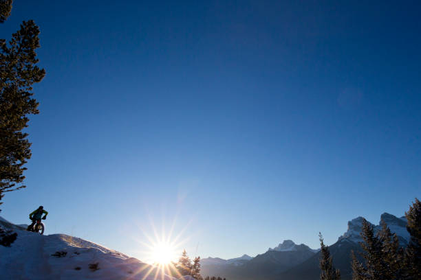 A man goes for a fatbike ride on a cold winters morning in Canmore, Alberta, Canada. Fatbikes are mountain bikes with oversized wheels and tires for riding on the snow.