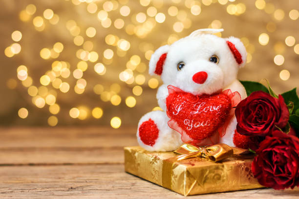 Plush toy bear, red roses and gift box. Valentines day Valentines day concept. White plush toy bear, red roses and gift box, on wooden blackboard with copy space for text. Selective focus. rose bouquet red table stock pictures, royalty-free photos & images