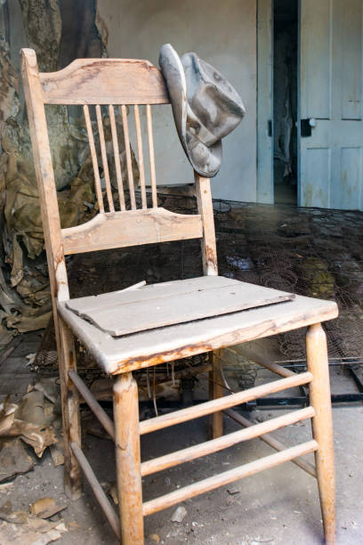 istock Old abandoned chair with a hat hanging off the post 1126805473
