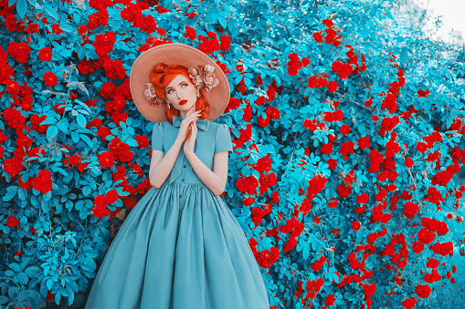 Valentines Day background. Spring rose flower garden. Sweet perfume. Trendy girl with red lips in dress. Gardening on farm. Flower perfume. Redhead woman on background of rose garden. Spring gardening