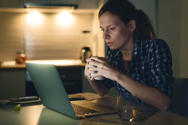 istock Young woman reading an e-mail on laptop and drinking coffee. 1126811058