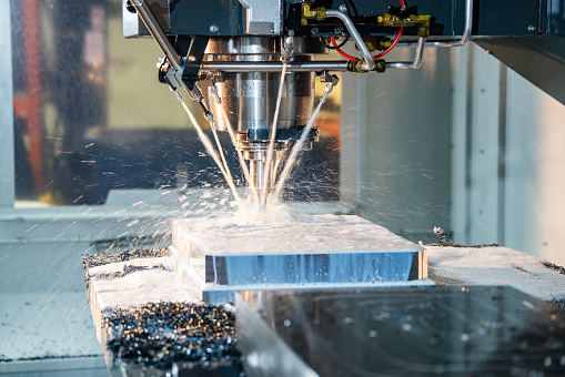 A modern CNC milling machine cutting steel in an industrial manufacturing machine shop.