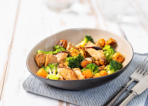 Top view of delicious and healthy salad with chiken, broccoli and roasted carrots on white table