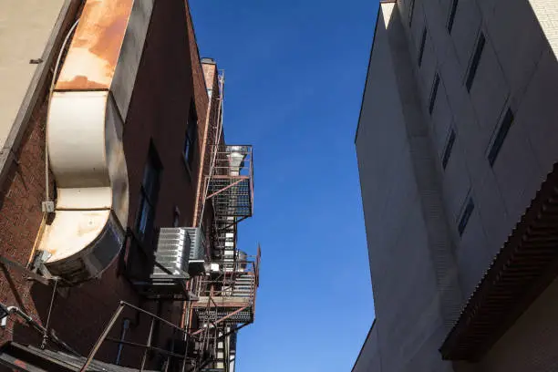 Photo of Fire escape rusty stairs and ladder, in metal, on a typical North American old brick building from Montreal, Quebec, Canada. These stairs, made for emergency, are symbolic of the architecture