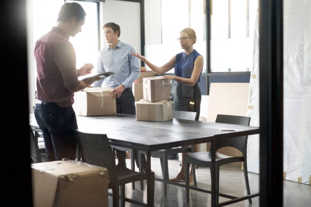 istock Businesswoman with boxes talking to colleagues 1126820178