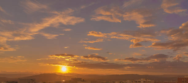 istock sunset scene with sun fall behind the clouds and mountains in background, warm colorful sky with soft clouds 1126821125