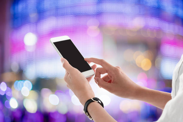 istock Woman hands holding and using smartphone with blank screen for your text or advertising isolated on blurred shopping mall lighting background.Mock up phone mobile concept. 1126822714