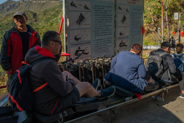 Fun Ride – ‘Toboggan’ down hill Toboggan at Mutianyu Great Wall, Beijing, China – October 7, 2018:  When visiting Mutianyu Great wall in China, you have several options to go up/down the walls. One of them is Toboggan. It is a fun ride to down the hill (no UP).  They are individual carts and you can carry all your stuff on your back or in front, just sit in the small cart and grab the handle(stick). You can control the speed with the stick. If you are too slow, you will have many other riders behind you. When the ride is over, you are back to the entrance at the bottom. mutianyu toboggan stock pictures, royalty-free photos & images