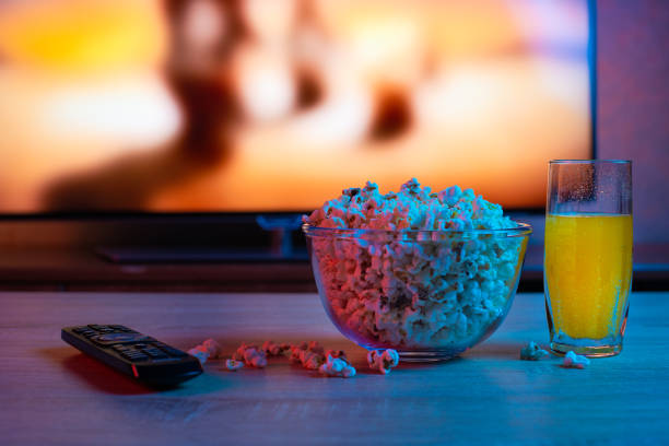 popcorn w szklanym talerzu z napojem na tle telewizora. kolor jasne oświetlenie. tło - popcorn snack bowl corn zdjęcia i obrazy z banku zdjęć