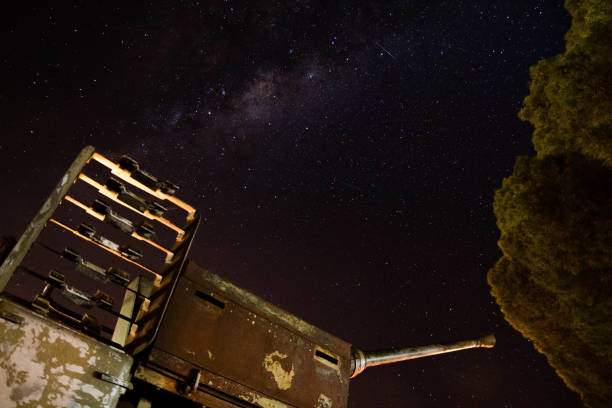 Entropy Old WWII Canon with Milky way in background and passing satellite. Photo shot in Henty, NSW, Australia. world war galaxy stock pictures, royalty-free photos & images