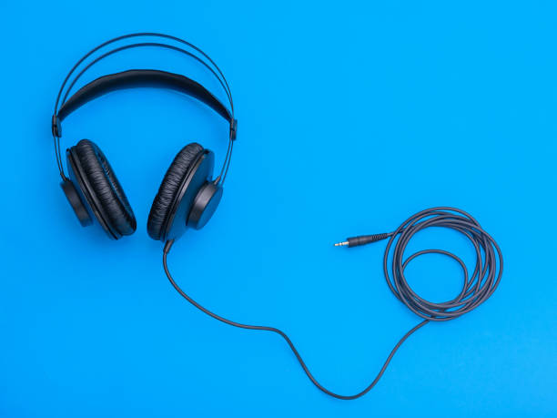 istock Black headphones with coiled cord on blue background. 1126833969