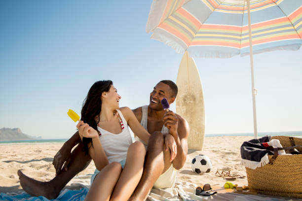 istock Happy couple holding popsicles at beach 1126838628