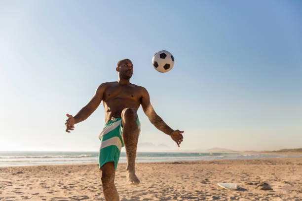 istock Man playing soccer at beach against clear sky 1126839253
