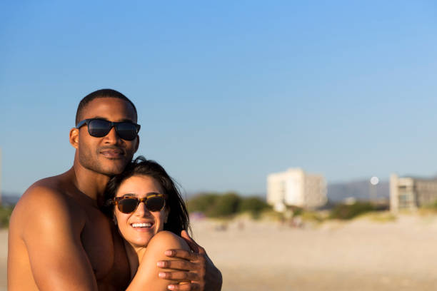 istock Confident man embracing woman at beach 1126839376