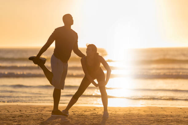 istock Couple exercising on shore at beach during sunset 1126839383