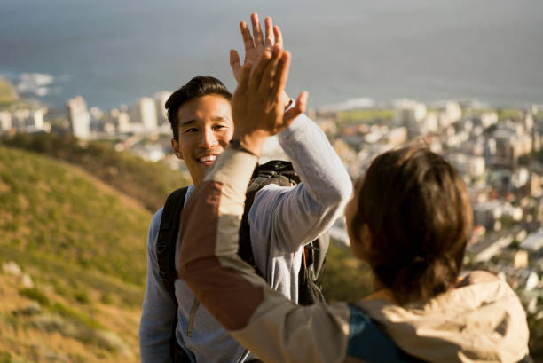 istock Happy hikers giving high-five on hill against city 1126840516