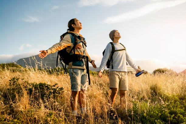 Hikers standing with arms outstretched on hill