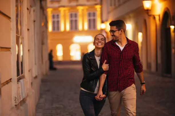 Happy young couple walking in a beautiful city in the evening