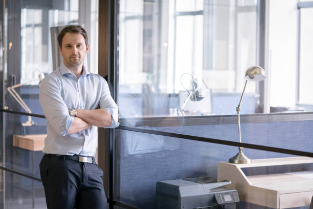 istock Businessman with arms crossed leaning on glass 1126845464