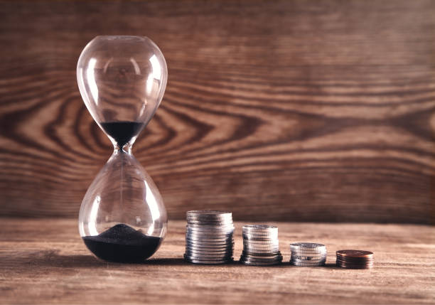 istock Coins and hourglass on a wooden background. 1126846466