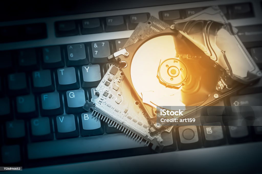 hacked computer hard drive on keyboard, concept of cybercrime Blue Stock Photo