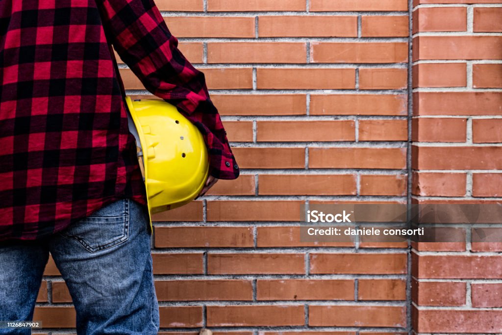 worker woman with safety helmet Girl at work safely with red brick wall Adult Stock Photo