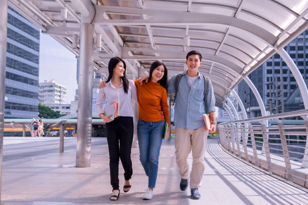istock Front view of three asian students walking and talking in an university campus. 1126850760