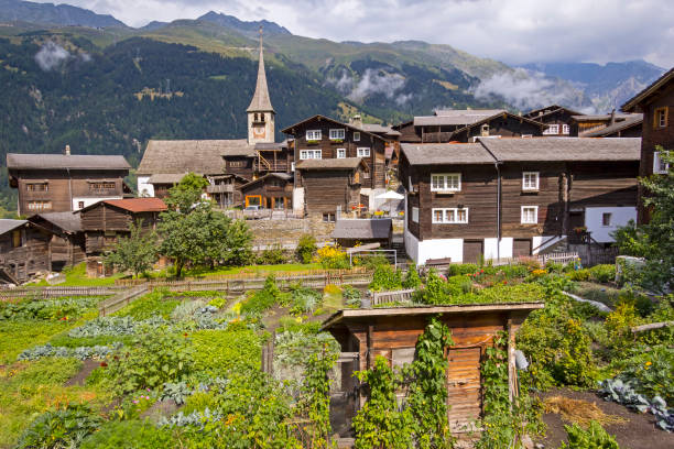 view of a rustic and idyllic large farm garden in a village in switzerland - engadine switzerland village church imagens e fotografias de stock