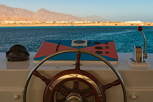 Ship control panel with steering wheel and engine accelerators on the captain bridge. Red Sea, Sinai Peninsula of Egypt.