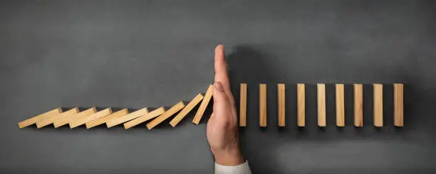 Photo of Chain Reaction In Business Concept, Businessman Intervening Dominoes Toppling
