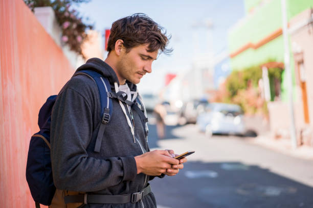 istock Male backpacker using smart phone on street 1126857583