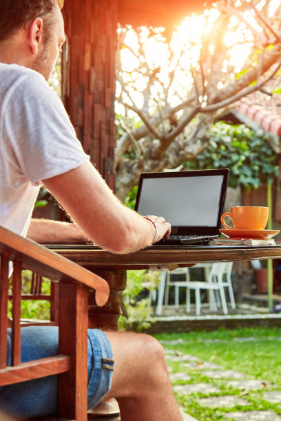 istock Man with coffee / tea and laptop on a home porch. 1126857767