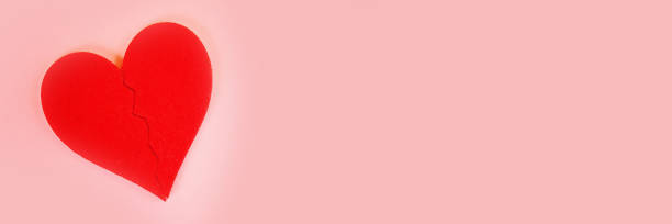 istock Red felt heart broken into two halves on a pink background. 1126858476