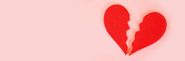 istock Red felt heart broken into two halves on a pink background. 1126858479