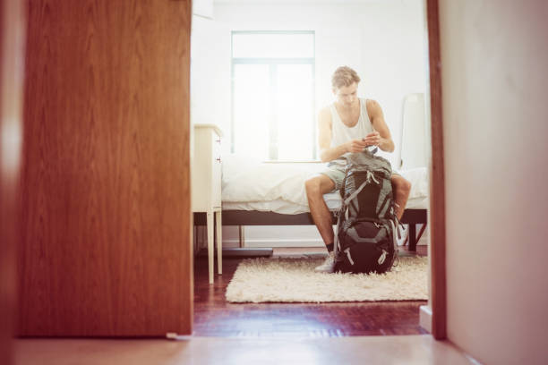 istock Young man packing backpack in hotel room 1126859899