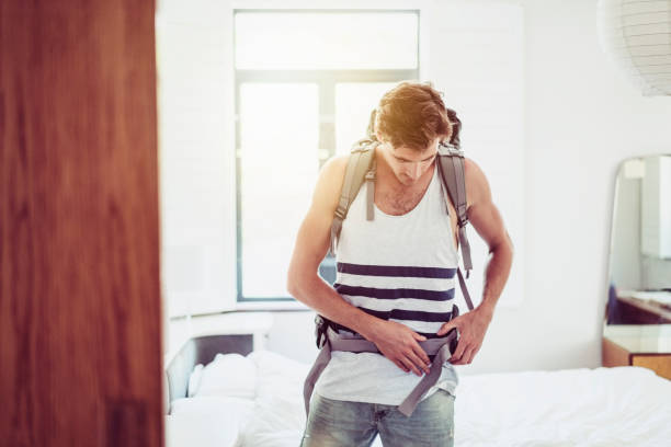 istock Man adjusting strap of backpack in bright room 1126860111