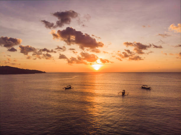 伝統的なバリ式ボート ドローンからバリ、インドネシアの写真の夕日ジンバランビーチのジュクン - jukung ストックフォトと画像