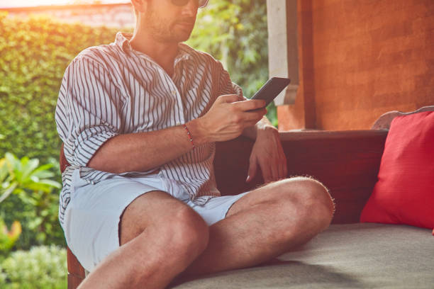 istock Man using smart phone on a terrace sofa in summertime. 1126863650