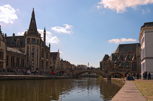 Ghent, Belgium– May 03, 2018: The stone St Michael's Bridge (Sint-Michielsbrug) over the Lys (Leie) River connects the Graslei and Korenlei Quays. Selective focus with wide angle lens.