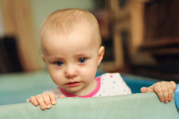istock pretty pathetic sad child standing in playpen 1126867201