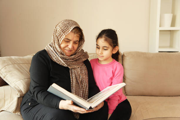 Multi-generation family, cute girl reading stories from a book with her grandmother at home.