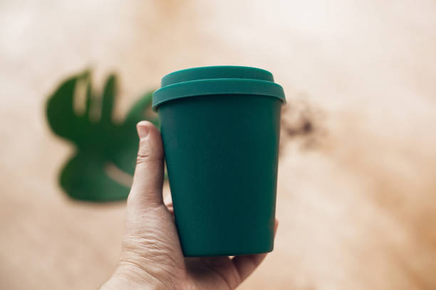 istock Ban single use plastic. Hand holding eco reusable coffee cup on wooden background. Coffee cup from bamboo fiber, zero waste concept.  Take away coffee in your cup. Sustainable lifestyle 1126877214