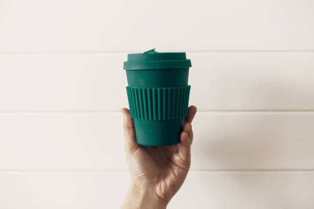 istock Ban single use plastic. Hand holding stylish reusable eco coffee cup on white wooden background. Green Cup from natural  bamboo fiber, zero waste concept. Make a choice. Take away coffee 1126878164